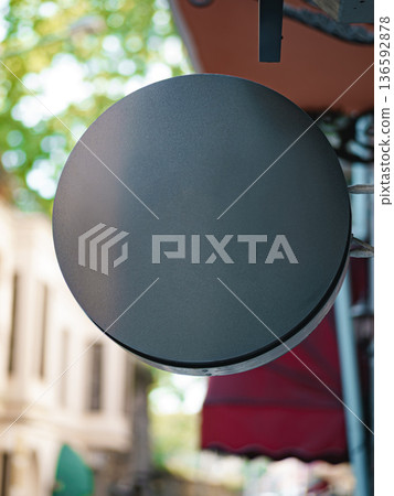 Round black sign on a street in a city with trees and buildings in the background Round black sign on a street in a city with trees and buildings in the background 136592878