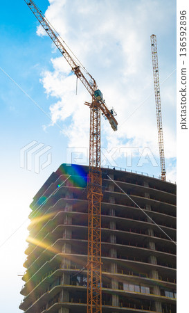 Construction site features crane and building under work during sunny day Construction site features crane and building under work during sunny day 136592896