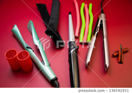 A pleat on a pink background, stylers and curling irons for straightening and creating curls, curlers of different shapes and sizes nearby. The concept of hair care, hairstyle, hairdressing. High A pleat on a pink background, stylers and curling irons for straightening and creating curls, curlers of different shapes and sizes nearby. The concept of hair care, hairstyle, hairdressing. High 136592931