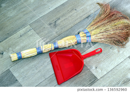 The broom and dustpan are lying on the floor. 136592960