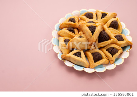 Purim celebration concept, jewish carnival holiday. Hamantaschen cookies over white neutral rose background Purim celebration concept, jewish carnival holiday. Hamantaschen cookies over white neutral rose background 136593001