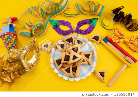 Frame made of carnival mask, rattles, Hamantaschen cookies and decor for Purim holiday on yellow background. 136593014