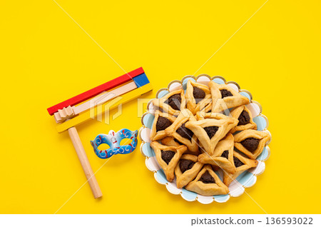 Frame made of carnival mask, rattles, Hamantaschen cookies and decor for Purim holiday on yellow background. 136593022