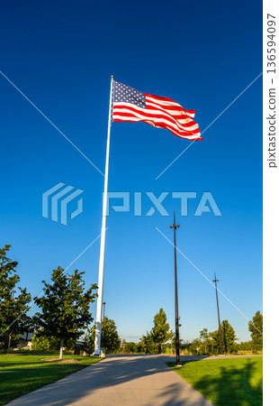 Omaha, Nebraska riverfront features a large American flag flying on a tall pole in a green park south of the I-480 bridge under a blue sky Omaha, Nebraska riverfront features a large American flag flying on a tall pole in a green park south of the I-480 bridge under a blue sky 136594097