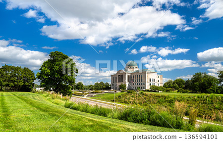 Iowa Judicial Branch Building in Des Moines. Historic limestone architecture features a copper dome and columns on a green lawn under a blue sky Iowa Judicial Branch Building in Des Moines. Historic limestone architecture features a copper dome and columns on a green lawn under a blue sky 136594101