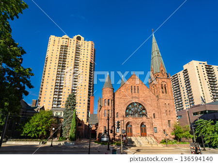 Central Presbyterian Church in St Paul Minnesota features historic Richardsonian Romanesque architecture with red sandstone and a tall green spire between modern buildings Central Presbyterian Church in St Paul Minnesota features historic Richardsonian Romanesque architecture with red sandstone and a tall green spire between modern buildings 136594140