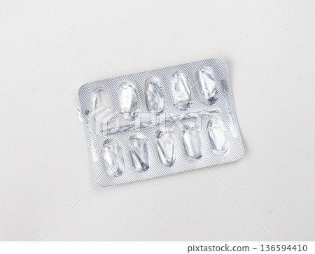 Empty foil blister pack for capsules on white background. Used medications. Pharmaceutical industry and pharmacy concept Empty foil blister pack for capsules on white background. Used medications. Pharmaceutical industry and pharmacy concept 136594410