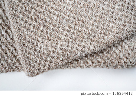 Folded knitted beige woolen blanket. Beige knitted blanket on white background. Flat lay, top view 136594412