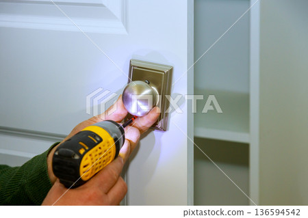 Repairing door handle with drill in home at new room Repairing door handle with drill in home at new room 136594542
