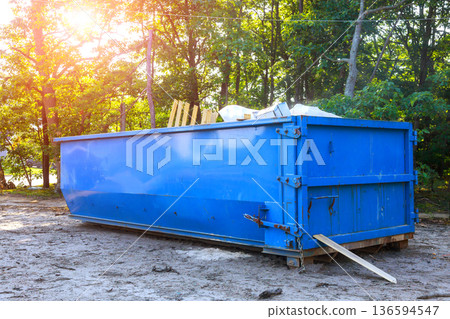 Construction site with blue metal waste dumpster filled with debris 136594547