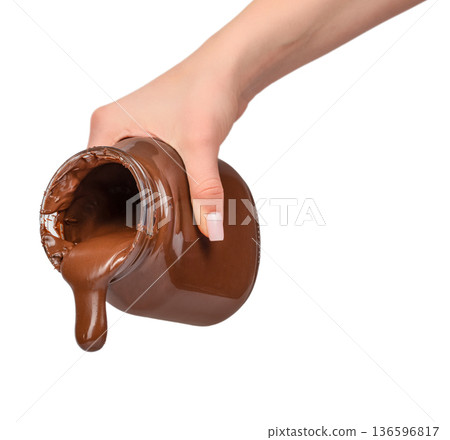Melted chocolate pouring from glass jar in female hand isolated on white Melted chocolate pouring from glass jar in female hand isolated on white 136596817