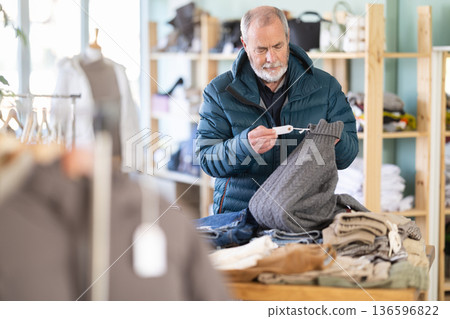Elderly man choosing jersey knitted sweaters 136596822