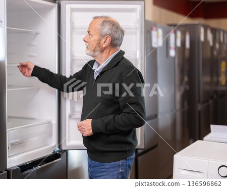 Elderly man choose modern fridge at supermarket Elderly man choose modern fridge at supermarket 136596862