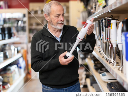 Senior man buyer examines immersion blender in detail before buying Senior man buyer examines immersion blender in detail before buying 136596863