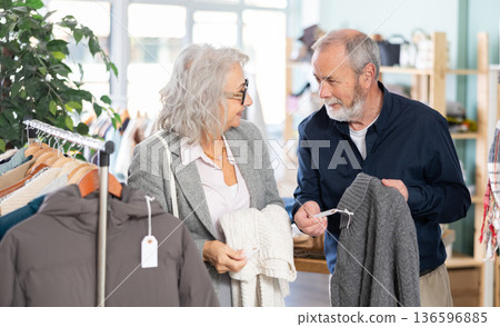 Elderly married couple chooses fashionable sweater in clothing store Elderly married couple chooses fashionable sweater in clothing store 136596885