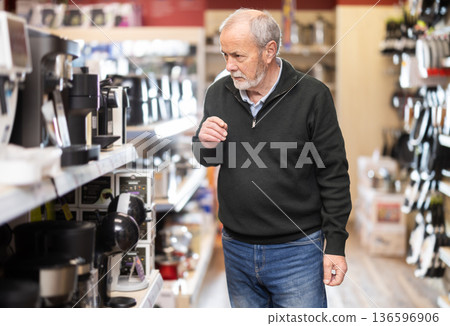 Elderly man chooses coffee machine in hypermarket 136596906