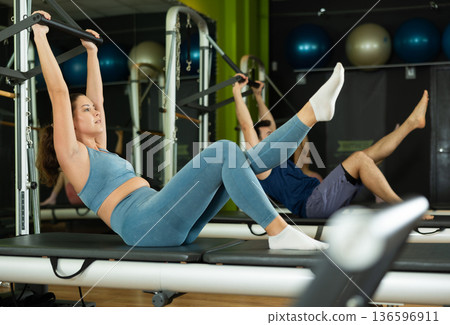 Young woman doing abdominal exercises on reformer Young woman doing abdominal exercises on reformer 136596911
