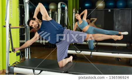 man is engaged in a group Pilates class and does abdominal exercises 136596924