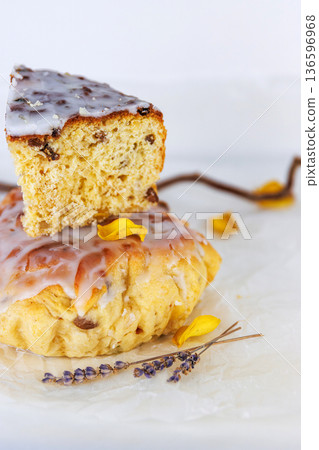 Glazed easter bread on crinkled parchment with a cut slice on top, styled with lavender sprigs and yellow petals. Selective focus Glazed easter bread on crinkled parchment with a cut slice on top, styled with lavender sprigs and yellow petals. Selective focus 136596968