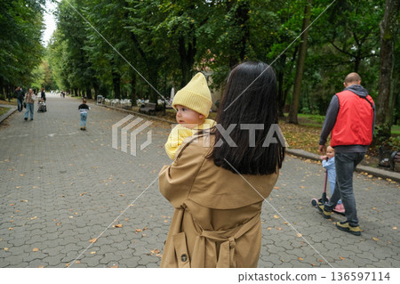 Mother Holding Baby in Yellow Outfit at Park Mother Holding Baby in Yellow Outfit at Park 136597114