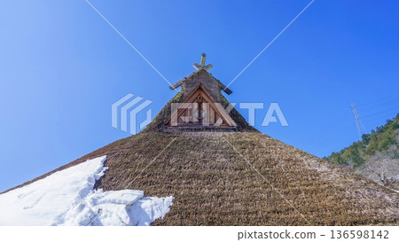 A view of traditional Japanese thatched roofs and remaining snow against the blue sky at Miyama Kayabuki Village 136598142
