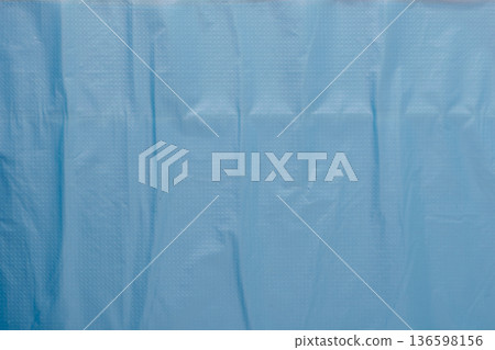 Crumpled light blue plastic film surface forming textured background 136598156
