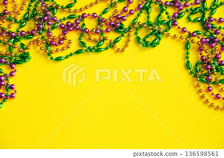 Mardi Gras concept. Multicolored beads on yellow background. Festive carnival symbols. Mardi Gras concept. Multicolored beads on yellow background. Festive carnival symbols. 136598561
