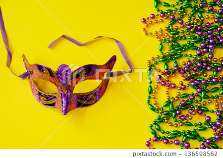Multicolored beads and carnival mask on yellow background. Mardi Gras concept. Fat Tuesday symbol. 136598562