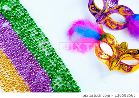 Two carnival masks with feathers and multi-colored beads on white background. Mardi Gras or Fat Tuesday symbol. Two carnival masks with feathers and multi-colored beads on white background. Mardi Gras or Fat Tuesday symbol. 136598565