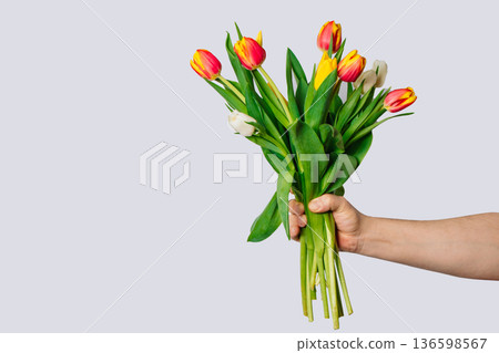 Man holds in his hand large bouquet of multi-colored tulips. 136598567
