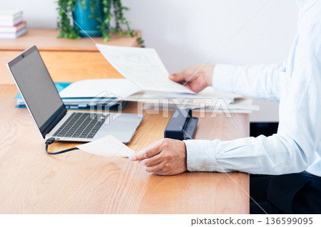 一名男子的手正準備提交他的報稅表 一名男子的手正準備提交他的報稅表 136599095
