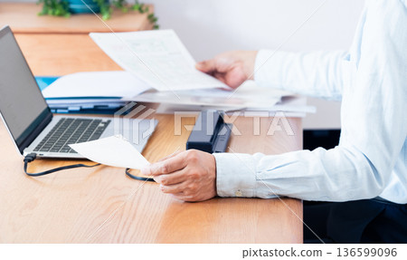 一名男子的手正準備提交他的報稅表 一名男子的手正準備提交他的報稅表 136599096