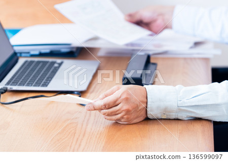 一名男子的手正準備提交他的報稅表 一名男子的手正準備提交他的報稅表 136599097