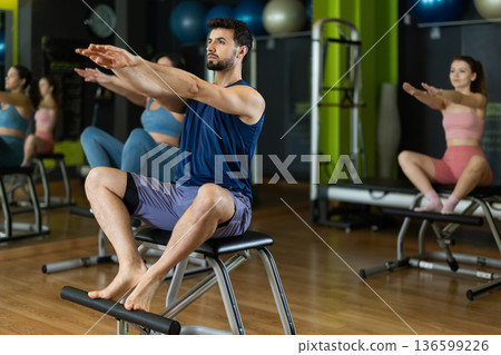 man doing exercises for his arms and legs in a Pilates class 136599226