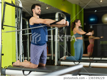 man doing arm strength exercises on reformer 136599229