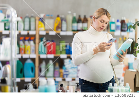 Pregnant woman scanning shower gel barcode with phone in store 136599235