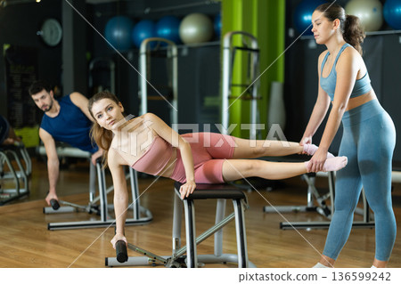 woman doing core stabilization and deep abdominal activation exercise on Pilates chair with trainer. 136599242