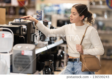 Girl buyer examines and choose coffee machine 136599243