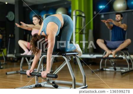 Young woman doing exercises for arms and posture on a pilates chair 136599278