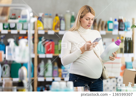 Pregnant woman scanning detergent barcode, checking ingredients Pregnant woman scanning detergent barcode, checking ingredients 136599307