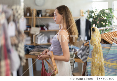 Selective young woman choosing something for summer in clothing store Selective young woman choosing something for summer in clothing store 136599309
