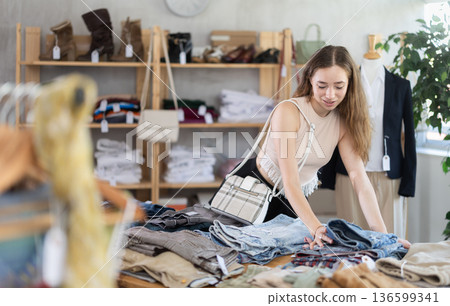 Selective young woman choosing pantaloons in clothing store Selective young woman choosing pantaloons in clothing store 136599341