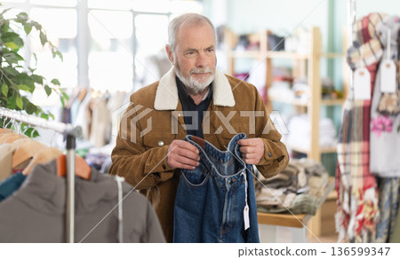 Family clothing store, senior man customer choose jeans Family clothing store, senior man customer choose jeans 136599347