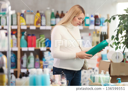 Pregnant woman choosing eco-friendly detergent in supermarket Pregnant woman choosing eco-friendly detergent in supermarket 136599351
