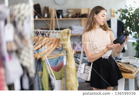Young woman chooses fashionable shoes in prestigious store Young woman chooses fashionable shoes in prestigious store 136599356