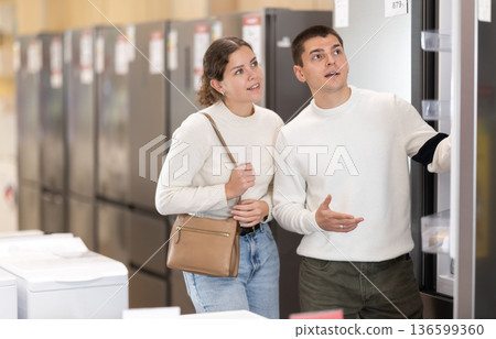 Girl with help of guy sales consultant choosing fridge Girl with help of guy sales consultant choosing fridge 136599360