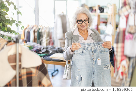 Family clothing store, senior woman customer choose jeans 136599365