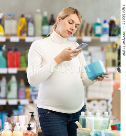 Pregnant woman scanning feminine pads in store Pregnant woman scanning feminine pads in store 136599368