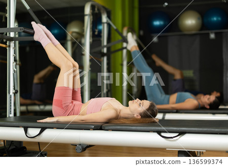 Young woman doing pelvic lift exercise on reformer machine Young woman doing pelvic lift exercise on reformer machine 136599374