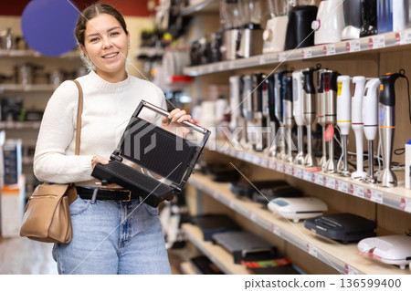 Woman choosing a waffle iron in a store Woman choosing a waffle iron in a store 136599400